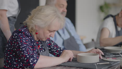 Three-elderly-people-work-on-a-potter's-wheel-in-slow-motion